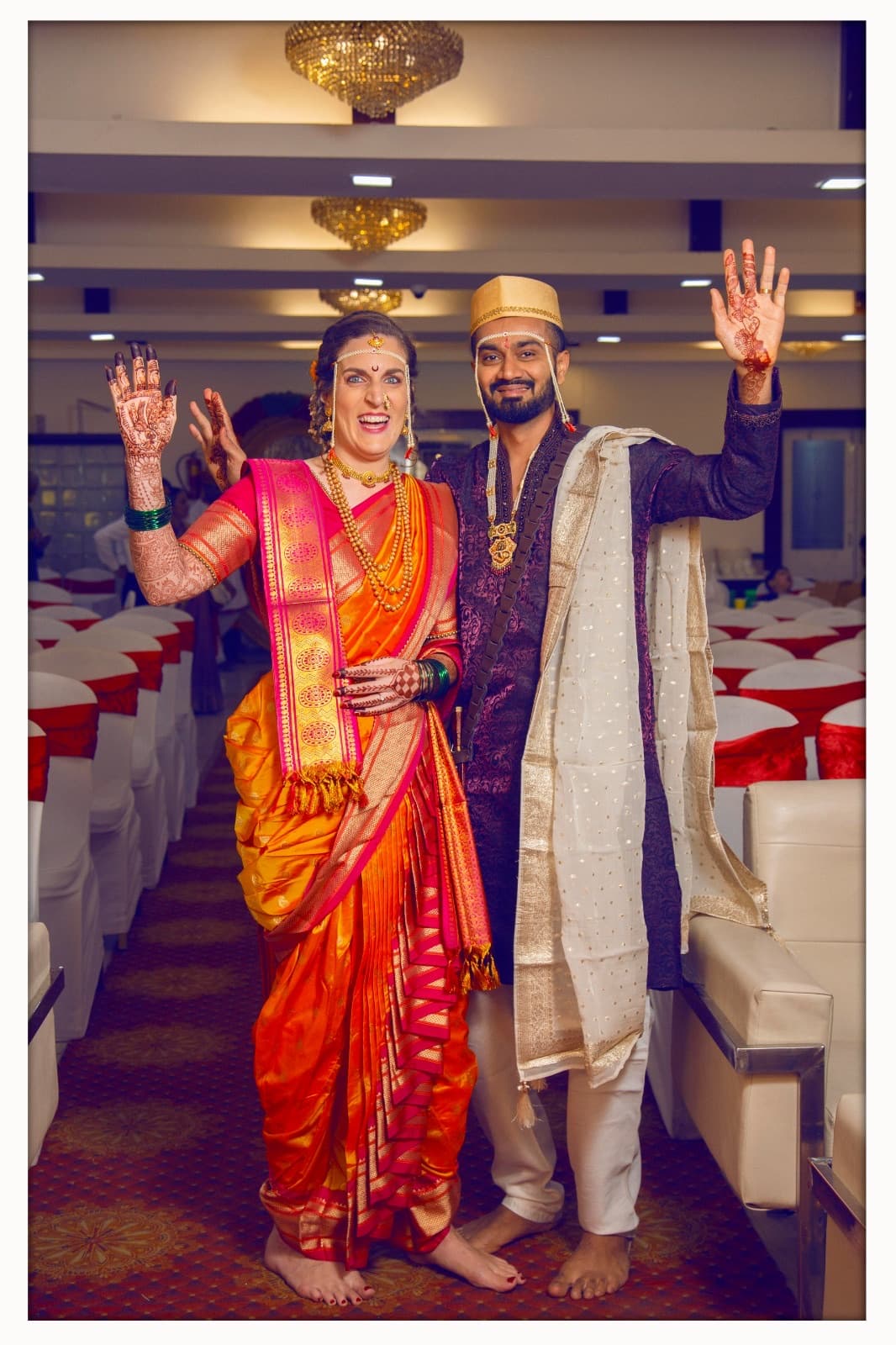 A couple in wedding clothes waving in a celebration hall